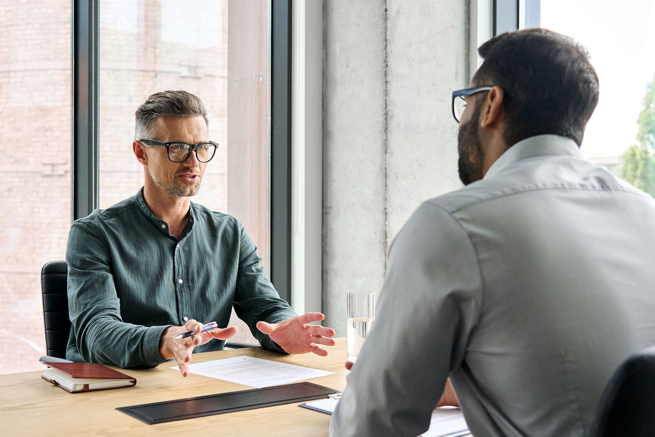 Manager adviser consulting client discussing financial partnership contract sitting at table in office
